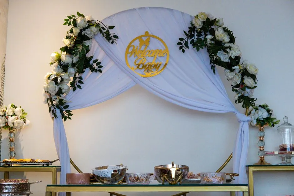 An elegant baby shower decoration setup with a floral arch