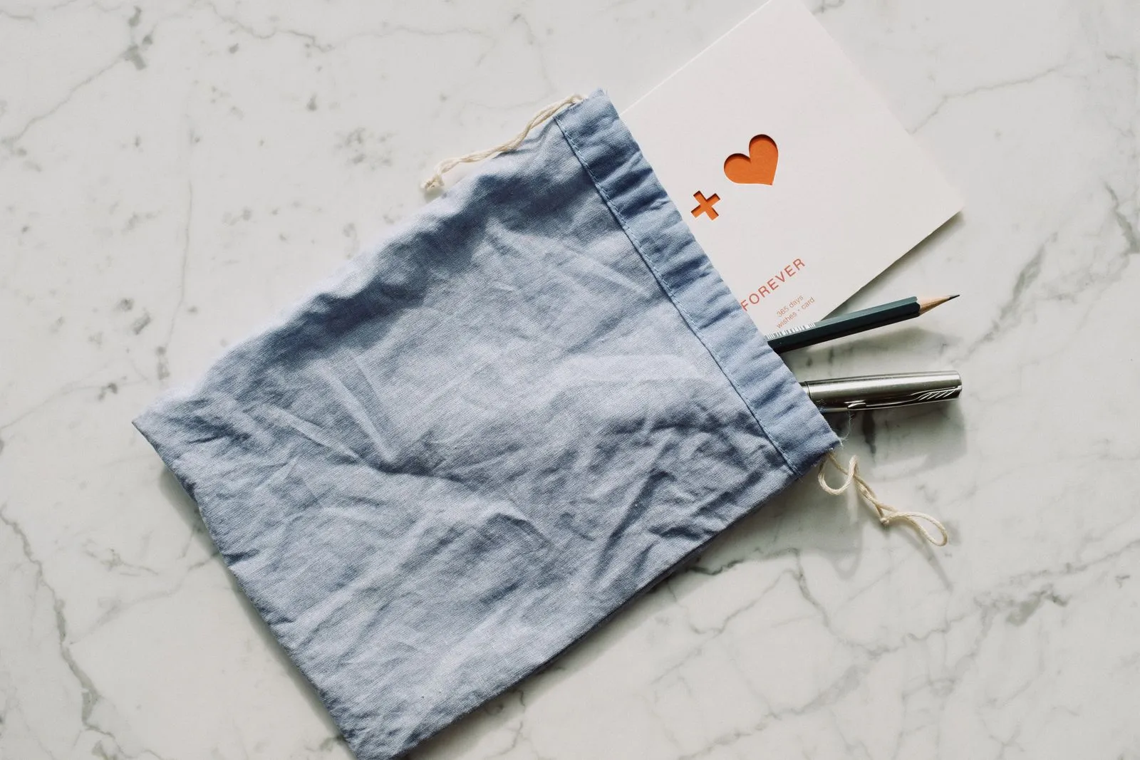 A blank postcard with a pen and pencil resting on a marble table